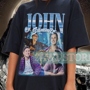May include: Black oversized t-shirt featuring a graphic print of four men and the text "JOHN Summer".