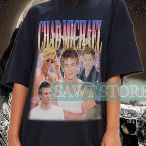 May include: Black oversized t-shirt with a vintage-style graphic print of the band Chad Michael. The print features a collage of the band members' faces with a pink, blue, and yellow color scheme.