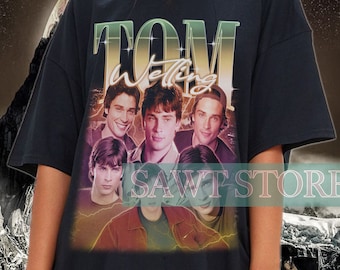 May include: Black oversized t-shirt with a vintage-style graphic of the band "Tom Welling" on the front. The graphic features five men in a band pose with the band name in large, stylized letters.