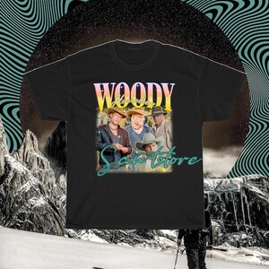 May include: Black t-shirt with a vintage-style graphic of a band called "Woody Santstore". The graphic features four men wearing cowboy hats and vests.