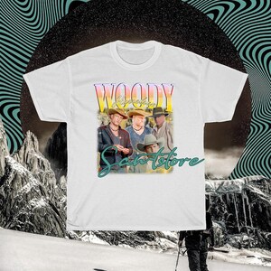 May include: White t-shirt with a vintage-style graphic of a band called "Woody" with the text "Sanstore" underneath.