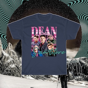 May include: A navy blue t-shirt with a retro-style graphic of Dean Winchester from the TV show Supernatural. The graphic features Dean and other characters from the show, with the text "Dean Winchester" and "Samstore" in pink and green.