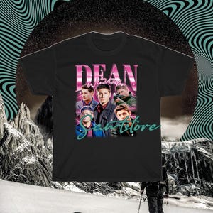 May include: Black t-shirt with a graphic print of Dean Winchester from the TV show Supernatural. The graphic features Dean and other characters from the show in a retro style with the text "Dean Winchester" and "Samstore" in pink and teal.