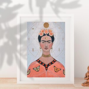 Op de afbeelding: Ingelijste kunstdruk met een portret van een vrouw met een bloemenkroon en gouden sieraden. Het kunstwerk heeft een geometrische achtergrond en een perzikkleurige top met vlinderdetails. Een klein Boeddha-beeldje staat in de buurt.