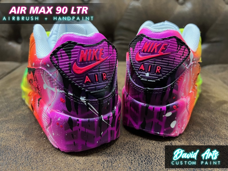 May include: Custom painted Nike Air Max 90 LTR sneakers with a vibrant rainbow gradient and black splatters. The back of the shoe features a black Nike swoosh with a pink outline and the text "NIKE AIR" in black.