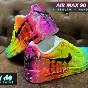 May include: Custom painted Air Max 90 LTR sneakers with a rainbow gradient and black accents. The shoes feature a white base with splashes of pink, yellow, orange, and blue paint. The text "AIR MAX 90 LTR" and "AIRBRUSH + HANDPAINT" is visible on the image.