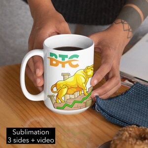Pode incluir: Caneca de cerâmica branca com um touro dourado e texto verde que diz "BTC" no lado. O touro está em pé em um gráfico de linha verde e colunas douradas.