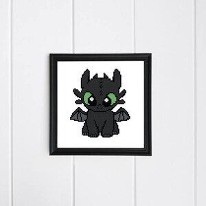 Puede incluir: Un dragón de dibujos animados negro y verde con ojos grandes y alas. El dragón está sentado sobre sus patas traseras con sus patas delanteras delante de él.