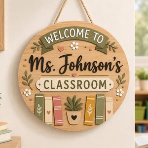 May include: Round wooden classroom sign with the text "WELCOME TO Ms. Johnson's CLASSROOM". The sign has a banner, floral accents, and a shelf with books and a potted plant. It hangs from a rope.
