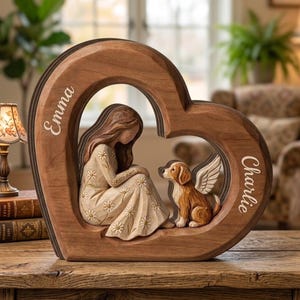 May include: A heart-shaped wooden sculpture featuring a carved figure of a person with long hair wearing a daisy-patterned dress sitting across from a small dog with angel wings. The names Emma and Charlie are engraved on the wooden frame.