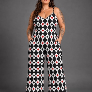 Op de afbeelding: Een mouwloze jumpsuit met een herhalend ruitpatroon in zwart en wit, geaccentueerd met rode harten en zwarte klaveren speelkaartsymbolen. Het kledingstuk heeft een V-hals, dunne spaghettibandjes en een wijde broek met zijzakken.