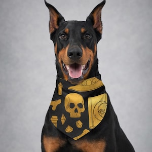 May include: A Doberman Pinscher wearing a black bandana with a gold skull and other occult symbols. The dog has a black and brown coat and is smiling. The bandana features a repeating pattern of gold illustrations on a black background.