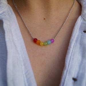 May include: A silver chain necklace with a rainbow of round, colorful beads.