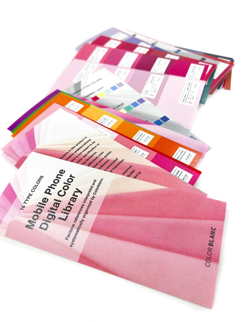 May include: A collection of color swatches fanned out, displaying a range of pink and magenta hues. The text "Mobile Phone Digital Color Library" is visible on the front swatch. Other swatches show color gradients and text labels, with a white background.