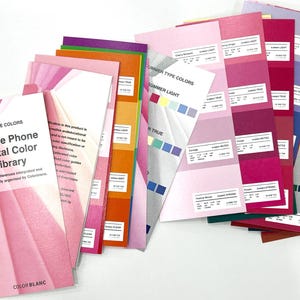 May include: A collection of color swatches and guides, featuring a pink cover with the text "Mobile Phone Digital Color Library." The swatches display various shades of pink, purple, and other colors, with text labels for each color. The image is well-lit and shows a variety of color palettes.