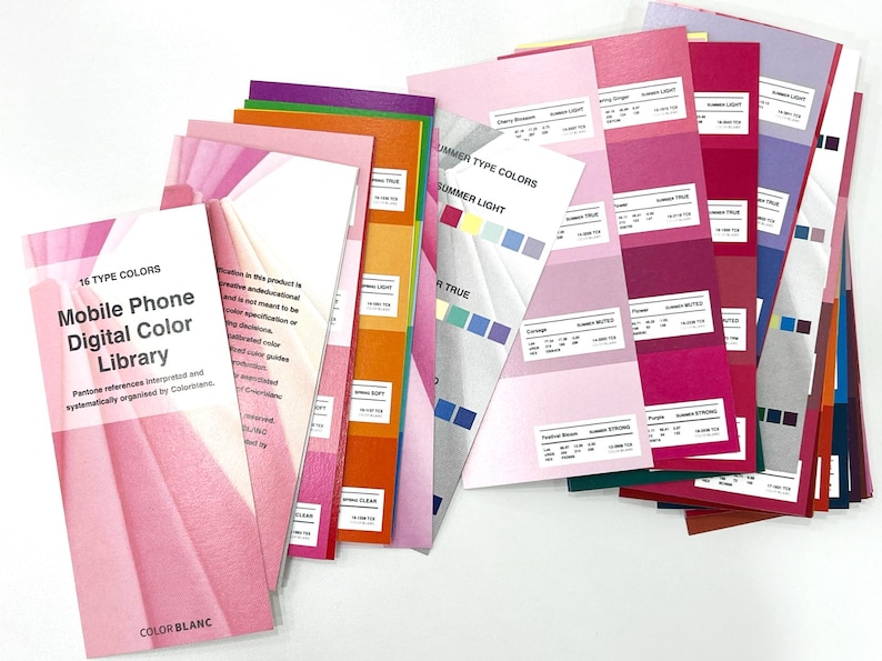 May include: A collection of color swatches and guides, featuring a pink cover with the text "Mobile Phone Digital Color Library." The swatches display various shades of pink, purple, and other colors, with text labels for each color. The image is well-lit and shows a variety of color palettes.