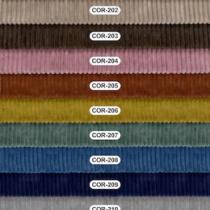 Pu&ograve; includere: Una collezione di undici campioni di tessuto a coste disposti orizzontalmente, ciascuno etichettato con un cartellino bianco. I colori includono crema, beige, marrone, rosa, ruggine, senape, ottanio, blu, blu navy, grigio e nero, con coste verticali.