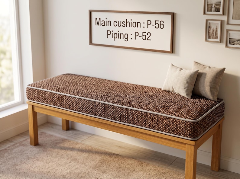 Pode incluir: Um banco de madeira com uma almofada castanha comprida e texturada com debrum claro. A almofada tem a etiqueta Main cushion: P-56 e Piping: P-52. Duas pequenas almofadas retangulares bege claro repousam no lado direito do assento.