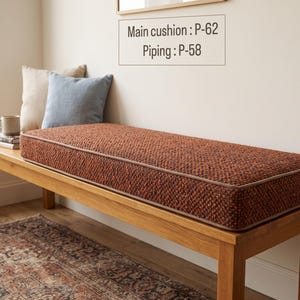 Pode incluir: Uma almofada retangular para banco em tecido entrela&ccedil;ado de cor laranja queimado com textura e debrum a condizer. A almofada apresenta uma etiqueta com o texto Main cushion : P-62 e Piping : P-58. A almofada est&aacute; sobre um banco de madeira.