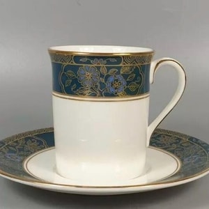 May include: A white porcelain teacup and saucer set with a gold trim and a blue and gold floral pattern.