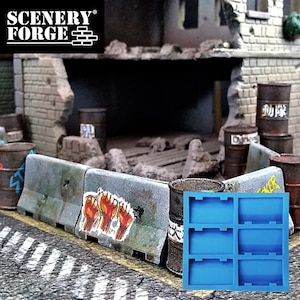 May include: A miniature diorama scene featuring a damaged brick building, concrete barriers with graffiti, and rusty barrels. A blue silicone mold with six rectangular cavities is in the foreground. The scene is designed for model building.
