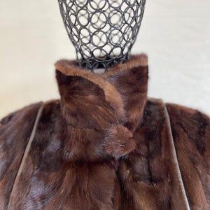 Pode incluir: Um casaco de pele castanho com gola alta e fecho de bot&atilde;o. O casaco tem um design elegante e &eacute; feito de pele de alta qualidade.