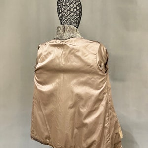 May include: A brown and white fur coat with a satin lining. The coat is shown on a mannequin.