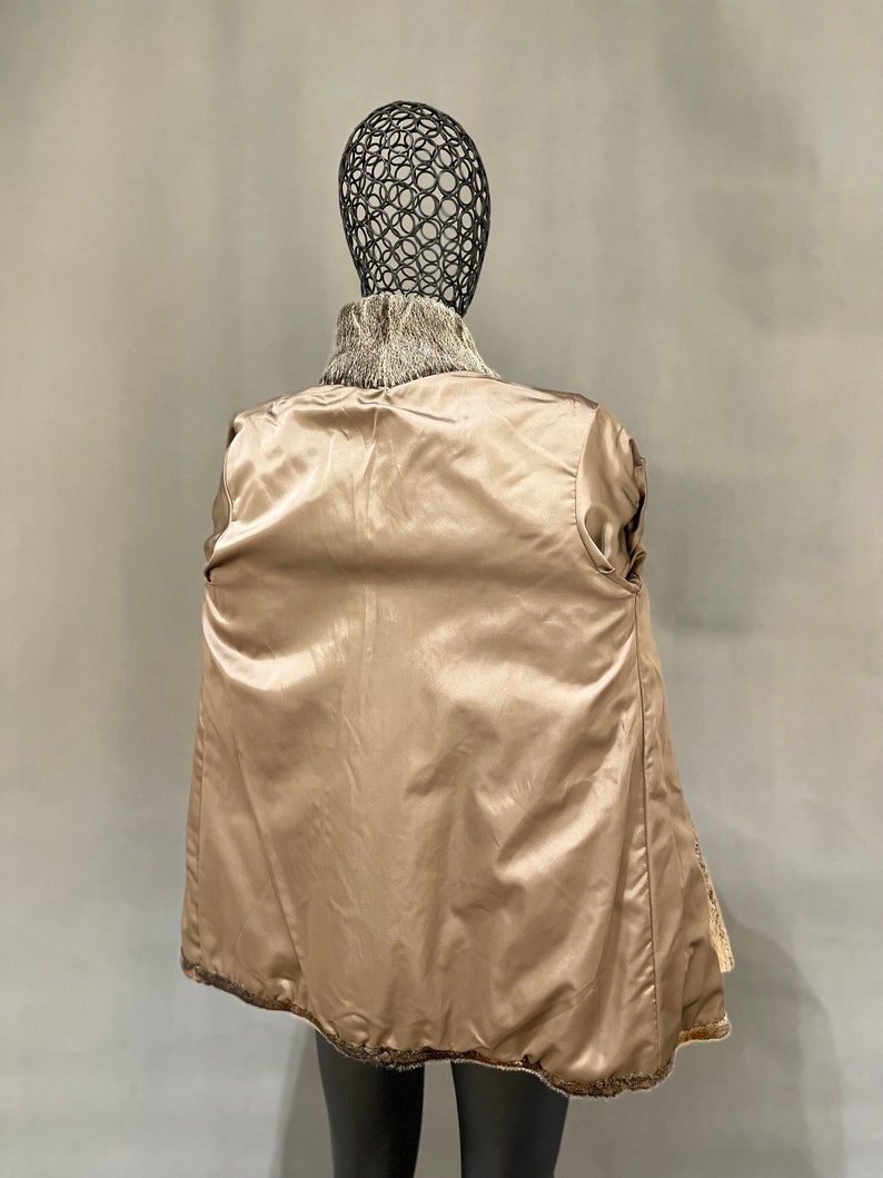 May include: A brown and white fur coat with a satin lining. The coat is shown on a mannequin.