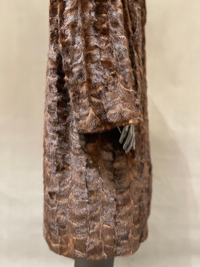 May include: A brown fur coat with a long, straight cut. The coat is made of a soft, luxurious fur and has a classic, elegant style.