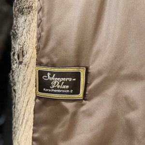 May include: A brown leather label with gold stitching and the text "Scheepers Pelze Korschenbroich 2" in a cursive font.