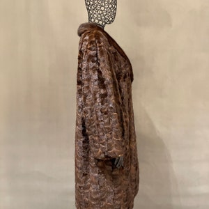 May include: A brown fur coat with a large collar. The coat is on a mannequin.