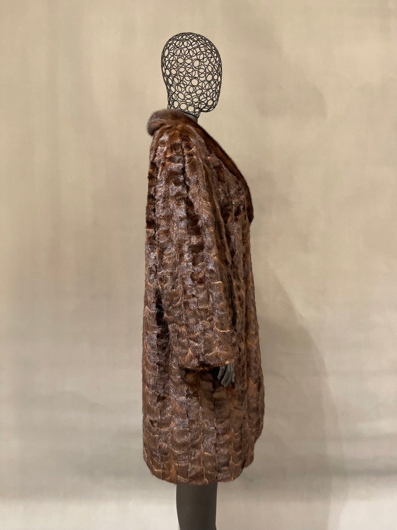 May include: A brown fur coat with a large collar. The coat is on a mannequin.