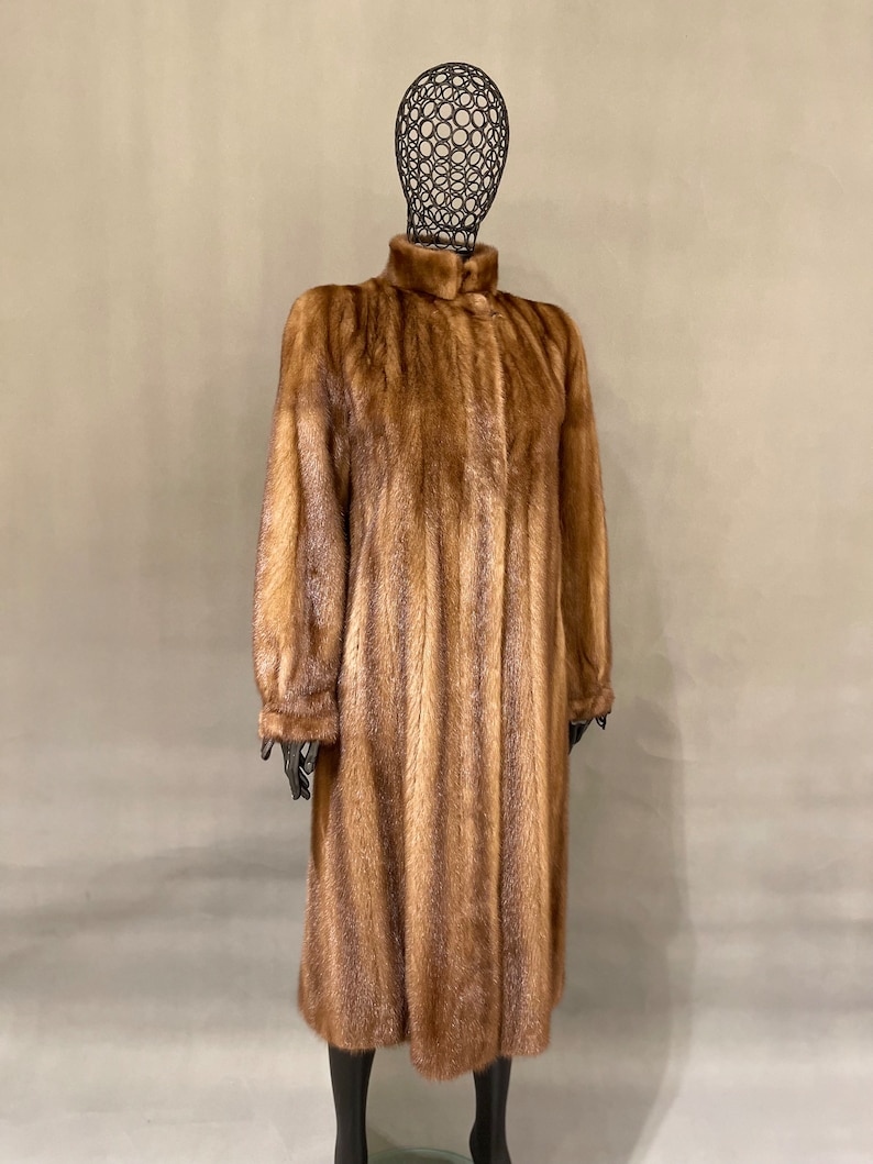 May include: A long brown fur coat with a high collar and a button closure.