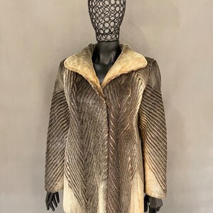 May include: A brown and white fur coat with a large collar. The coat has a chevron pattern and is on a mannequin.