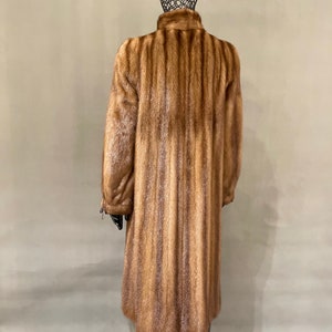 May include: A long brown fur coat with a vertical striped pattern.