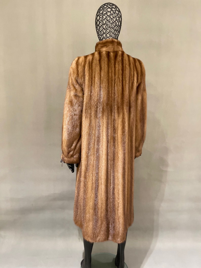 May include: A long brown fur coat with a vertical striped pattern.