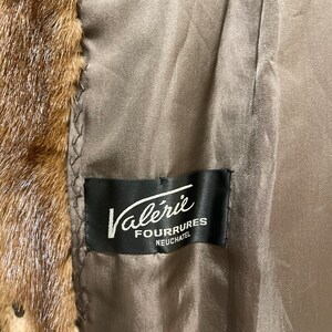May include: A brown fur coat with a black label that reads "Val&eacute;rie Fourrures Neuch&acirc;tel".