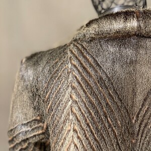 May include: A brown and white fur jacket with a chevron pattern. The jacket is made of a soft, luxurious fur.