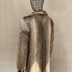 May include: A brown and white fur coat with a chevron pattern. The coat is on a mannequin.