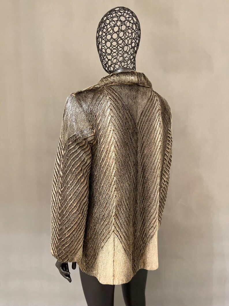 May include: A brown and white fur coat with a chevron pattern. The coat is on a mannequin.