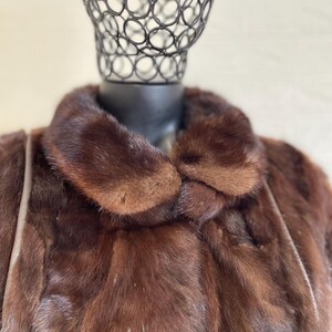 Pode incluir: Uma jaqueta de pele castanho com uma gola grande. A jaqueta &eacute; feita de uma pele macia e luxuosa e tem um design cl&aacute;ssico.