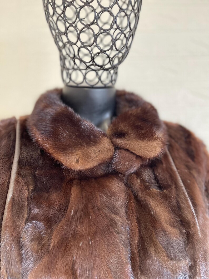 Pode incluir: Uma jaqueta de pele castanho com uma gola grande. A jaqueta &eacute; feita de uma pele macia e luxuosa e tem um design cl&aacute;ssico.