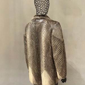 May include: A brown and white fur coat with a chevron pattern. The coat is on a mannequin.