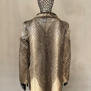 May include: A brown and white fur coat with a chevron pattern. The coat is on a mannequin.