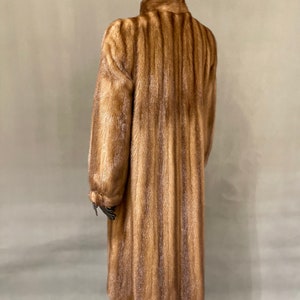 May include: A long brown fur coat with a high collar. The coat is made of a soft, luxurious fur and has a classic, elegant style.