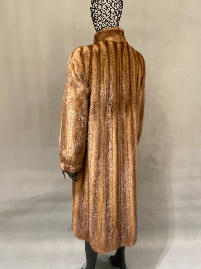 May include: A long brown fur coat with a high collar. The coat is made of a soft, luxurious fur and has a classic, elegant style.