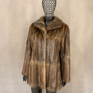 May include: A brown fur coat with a collar. The coat is on a mannequin.