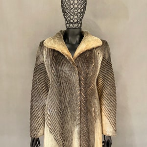 May include: A brown and white fur coat with a chevron pattern. The coat has a large collar and a button closure.