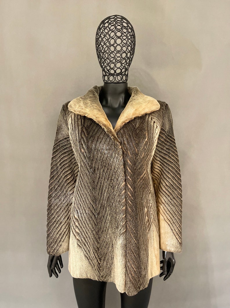 May include: A brown and white fur coat with a chevron pattern. The coat has a large collar and a button closure.