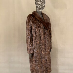 May include: A long brown fur coat with a large collar. The coat is made of a soft, luxurious fur and has a classic, elegant style.